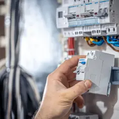 Dłoń montuje bezpiecznik w skrzynce elektrycznej z przewodami.